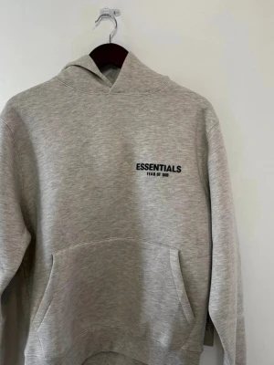 Grå Essentials hoodie - Jag säljer min Essentials hoodie för att jag har inte på mig den längre. Den är använd men ändå i jätte bra skick och man kan få fler bilder om man vill och priset kan sänkas vid snabb köp.   Str är xxs och passar folk som är 160-165