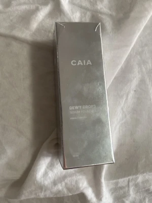 CAIA Dewy Drops Serum Foundation - CAIA Dewy Drops Serum Foundation i nyansen Dewy Drops. Kommer i en snygg glasflaska med silvrig pump och lock. Ger en återfuktande, naturlig finish och innehåller vitamin E. Förpackningen är stilren och reflekterande i silver. Innehåller 30 ml. Helt oanvänd fick hem för 1 timme sendan men helt fel färg.