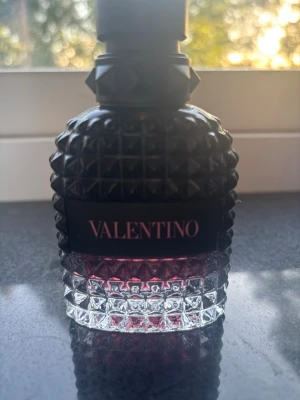 Valentino parfym med nitar - Säljer en lyxig parfym från Valentino i en cool, nitmönstrad glasflaska. Flaskan är svart upptill och övergår till transparent med en hint av rosa i botten. Märket står tydligt på flaskan och designen känns både modern och exklusiv. Skulle tippa på cirka 30 ml kvar  skriv till mig för mer bilder 100 procent äkta inköpt på kicks skriv dm om ni vill veta exakta mängd