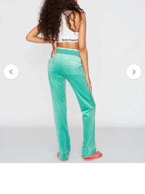 Mintgröna velourbyxor Juicy Couture - Säljer ett par mintgröna mjukisbyxor från Juicy Couture i mjuk velour. Byxorna har raka ben, två bakfickor med lock och knappdetaljer. Perfekta för en chill och trendig look.