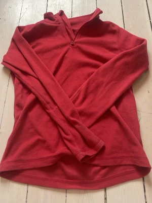 Skid underställ tröja - Skid underställ  röd fleece-tröja med lång ärm och halv dragkedja framtill. Perfekt för lager-på-lager och har en enkel, stilren design utan synligt märke. Mjuk och skön känsla, passar till många olika outfits.