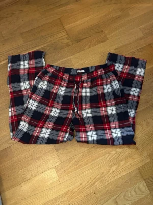 Rutiga mjukisbyxor från Cubus - Säljer ett par mjukisbyxor med klassiskt rutigt mönster i rött, mörkblått och vitt. Byxorna har snörning i midjan och fickor på sidan. Byxorna är från Cubus och är i storlek M. Pris kan diskuteras 