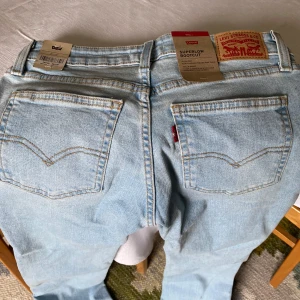 Levi's ljusblå bootcut jeans - Säljer ett par klassiska ljusblå Levi's jeans i bootcut-modell. Jeansen har normal passform, fem fickor och är tillverkade i bomull. Perfekta för dig som gillar en tidlös denimlook med lite utsvängda ben. Helt oanvända!
