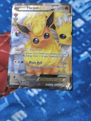 Pokémonkort Flareon EX - Säljer ett Pokémonkort med Flareon EX-motiv. Kortet har färgglad design med Flareon, Jolteon och Vaporeon på framsidan. Text och effekter på engelska, klassisk blå baksida med Pokéball. Perfekt för samlare eller Pokémonfans. Pris kan bli discoterad