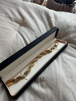 Guldfärgat armband från Indossa - Säljer ett snyggt guldfärgat armband från Indossa by Sweden. Armbandet har en tvinnad kedja och robust lås, levereras i original ask. Perfekt accessoar för att lyfta din outfit. 8 mm