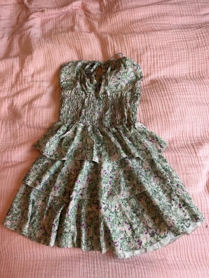 Strapless blommig klänning - Somrig klänning med gröna och lila blommönster, strapless och volangkjol, dessutom stretchigt material så passar flera storlekar