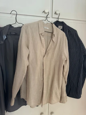 Skjortor x3 - Paket av tre stycken skjortor. Samtliga i väldigt bra skick. En linne skjorta + två mer ”vanliga” skjortor. Storlek M. Linne skjortan och den gråa aldrig använts, blå randiga är använd