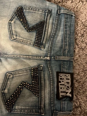 Rock & Republic ljusblå jeans - Säljer ett par ljusblå jeans från Rock & Republic Jeansen här en cool stil men nitar på fickorna. Jeansen är väl använda och är lagade i skrevet men de syns inte❤️
