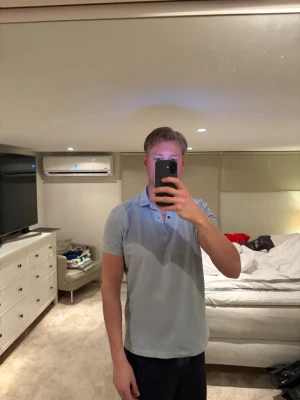 Ljusblå Massimo dutti pike - Säljer en ljusblå polotopp från Massimo dutti med klassisk krage och knappar framtill. T-shirten har korta ärmar och är tillverkad i mjuk bomull, perfekt för en avslappnad och stilren look.