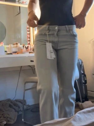 Ljusgrå raka jeans med tag kvar - Säljer ett par ljusgrå jeans med rak passform och klassisk femficksdesign. 