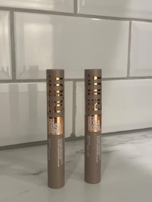 Maybelline Cils Sensational Body Mascara - Säljer två Maybelline Cils Sensational Body mascara i en snygg beige tub med metallic detaljer. Perfekt för att ge volym och definition till dina fransar. Tuben är slank och stilren med tydlig logga och text i guld. Passar dig som vill ha fylliga och separerade fransar.