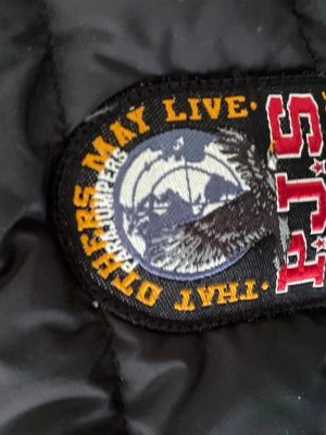 Svart dunjacka från Parajumpers - Säljer en svart dunjacka från Parajumpers med snyggt märke på axeln och orange detaljsöm. Jackan har quiltad design och är perfekt för kalla vinterdagar. Klassisk look med dragkedja och varm vaddering.