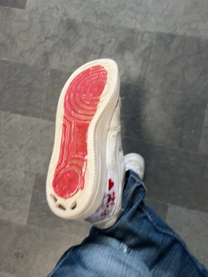 Lobs - Unika vita sneakers med röd detalj på sulan och små röda hjärtan på sidan. Skorna har en klassisk låg siluett och är tillverkade i läder eller syntetmaterial. Perfekta för dig som vill sticka ut med coola detaljer.