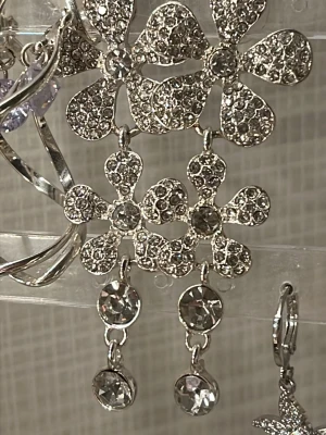 Glittriga blomformade örhängen i silver - Snygga örhängen i silverfärg med stora blommor täckta av gnistrande stenar. Hängande design med extra kristaller längst ner som ger extra bling. Perfekta för dig som gillar att sticka ut och vill ha något riktigt glammigt till öronen. Orginal pris: 350kr mitt pris 180kr