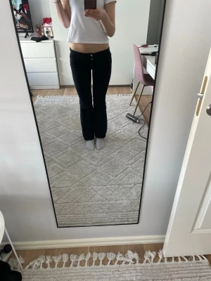 Svarta bootcut jeans med låg midja - Säljer ett par svarta bootcut jeans med låg midja och klassisk femficksdesign. Jeansen har en tight passform upptill och släpper ut vid benen för en snygg siluett. Perfekta till en trendig och avslappnad stil. Materialet är troligtvis bomull med stretch.