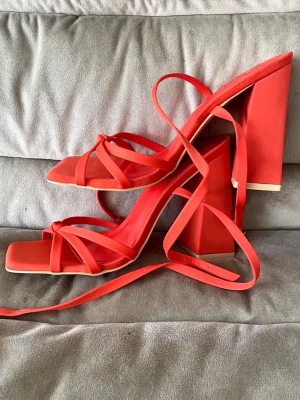 Korallfärgade pumps med blockklack och remmar - Snygga pumps med fyrkantig tå, bred blockklack och tunna remmar som snöras runt ankeln