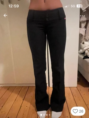Svarta bootcut kostymbyxor från Miss Sixty - Säljer ett par svarta bootcut kostymbyxor från Miss Sixty med låg midja och tre knappar framtill. Kostymbyxorna har en tight passform upptill och släpper ut vid benen. Klassisk röd Miss Sixty-logga vid fickan. Materialet känns stretchigt och bekvämt. Bilderna är lånade från hon jag köpte de av. Jättefina men tyvärr för stora för mig😔 skriv till mig för egna bilder❤️de har inga tecken på användning, har även en liten slits därnere men de kan man enskelt sy igen om man inte vill ha den. 
