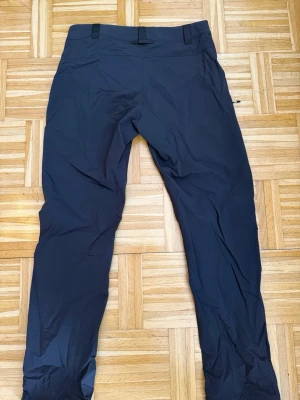 Svarta cargobyxor från Haglöfs L - Säljer ett par svarta cargobyxor från Haglöfs i storlek L. Byxorna har en clean look med bälteshällor och är tillverkade i ett slitstarkt, stretchigt material som passar perfekt för aktiva dagar. Snygg och funktionell design med minimalistiska detaljer.