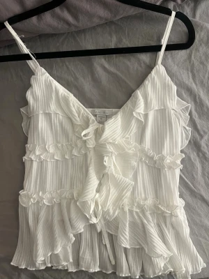 vitt sommar linne - säljer ett vitt sommar linne, med volanger och knyten fram till tröjan. perfekt för en avslappnad och varm sommar look