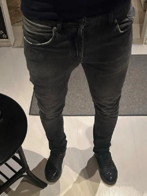 Svarta slim fit jeans replay - Säljer ett par svarta slim fit jeans med klassisk femficksmodell och normal midja. Jeansen har en snygg tvättad look och smal passform som sitter tajt längs benen. Perfekta för en trendig och avslappnad stil.