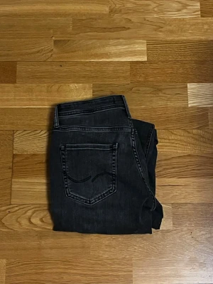 Svarta slim fit jeans från Jack & Jones - Snygga svarta slim fit jeans från Jack & Jones med klassisk femficksdesign. Jeansen har normal midja och raka ben. Tillverkade i stretchigt denim. Perfekta till en avslappnad stil. Motsvarar Replay anbass. Stl W30 L32