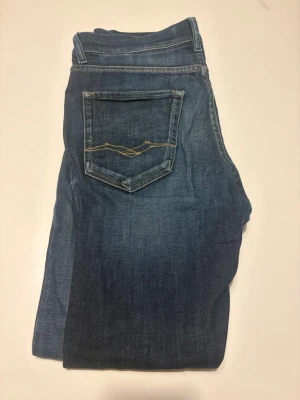 Mörkblå replay jeans, THAD - Snygga mörkblå jeans med raka ben och klassisk femficksdesign. Jeansen har kontrastsömmar och en diskret bakficka med broderad detalj. Perfekta till vardagslooken och tillverkade i slitstarkt denimtyg. Thad Replay jeans