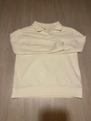 Vit collagetröja med krage - Snygg vit collagetröja med klassisk krage och långa ärmar. Tröjan har en relaxed fit och ribbade muddar vid ärmslut och nederkant. Perfekt till jeans eller chinos för en clean och enkel stil.