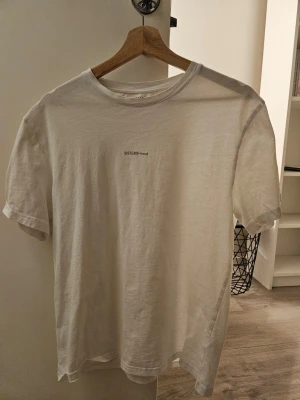 Vit t-shirt från EAST WEST - Vit t-shirt från EAST WEST med trycket 'SISTERS-hood' på bröstet. Endast använd 2-3 gånger, helt ny.