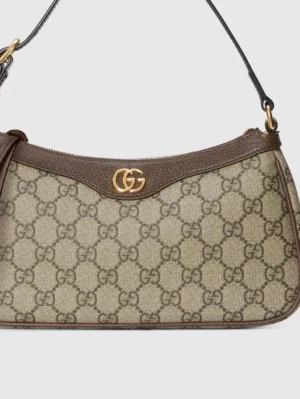 Gucci beige monogram handväska - Snygg beige handväska från Gucci med klassiskt GG-monogram över hela väskan. Väskan har bruna läderdetaljer, guldfärgad GG-logga framtill och en axelrem i läder. Perfekt accessoar för dig som gillar lyxig och tidlös design. En AA kopia som är i gott skick, aldrig använd.