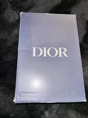 Svarta Dior b30 - Snygga svarta Dior sneakers med tydlig Dior-logga på sidan och coola detaljer i vitt och grått. Skorna har en chunky sula och sportig design som sticker ut. Perfekta för dig som vill ha något exklusivt och trendigt i garderoben. DEM ÄR JÄTTE ANVÄNDA MEN DET MESTA FÖRSVINNER OM DU SLÄNGER IN DEM I TVÄTTMASKIN.Sulan skulle också behövas limmas fast