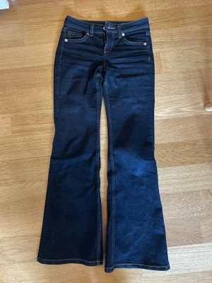 Mörkblå bootcut jeans från H&M - Snygga mörkblå jeans från H&M med låg midja och bootcut passform. Endast använda ett fåtal gånger. Säljer då de är för korta på mig som är 175cm. Nypris 349kr