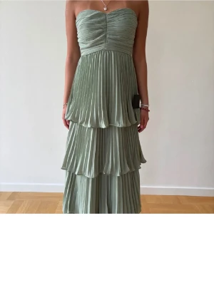 Ljusgrön axelbandslös långklänning - Säljer min balklänning. Är 155 cm lång. Sydde upp den lite för den va för lång. 