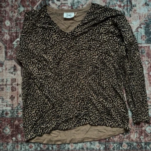 Leopardmönstrad tröja med V urringning - Säljer en snygg leopardmönstrad tröja. Tröjan har V-ringning, långa ärmar och är i mjukt, stretchigt material. Färgen är brun med svarta leopardfläckar. Skulle säga att den är i storlek medium men sitter lite oversized som small också i en mer chill passform.