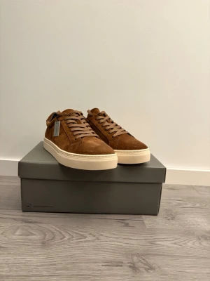 Bruna sneakers i mocka från Common Projects - Snygga bruna sneakers i mocka från Vagabond. Klassisk låg modell med stilren design. Perfekta för dig som gillar minimalistisk och clean stil. Storlek 40 men jag skulle säga att dem passar 41! Nypris: 1400kr✅aldrig använda!