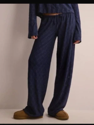 Mörkblå loungewear-set med vida byxor - Mysigt loungewear-set i mörkblått med långärmad topp och vida byxor med dragsko i midjan. Tillverkat i mjukt, stretchigt material som passar perfekt för avslappnade dagar hemma. Enkel och stilren design.