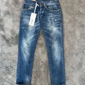 Dondup george - Snygga blå jeans från Dondup med slitna detaljer. Klassisk femficksmodell med orange sömmar och diskret logga bak. Jeansen har rak passform och är tillverkade i mjukt bomullsjeans.