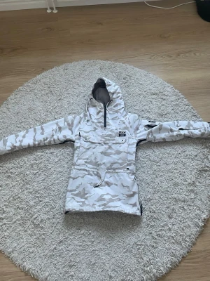 Vit camo vindjacka från Dope - Säljer en snygg vit vindjacka med camomönster från Dope. Jackan har huva, dragkedja i halsen, stor ficka framtill och justerbar midja. Säljer pga den har blivit för liten. Den är i storlek 2Xs men passar runt Xs/s🥰 