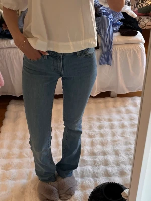 Ljusblå bootcut jeans från Levi's - Säljer ett par ljusblå bootcut jeans från Levi's med klassisk femficksdesign och normal midja. Jeansen har en snygg passform som sitter tajt upptill och släpper vid bensluten. Perfekta till sneakers eller boots!