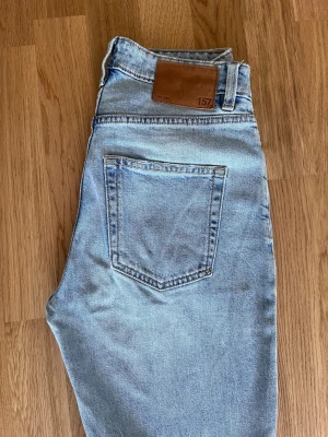 Ljusblå raka jeans från 157 - Ljusblå jeans med rak passform från 157. Klassisk femficksmodell med hög midja och läderpatch bak i midjan. Jeansen är tillverkade i denim och har en tidlös look som passar till det mesta.