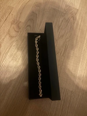 Guldfärgat armband från Kejsar - Snyggt guldfärgat armband från Kejsar med tvinnad kedjedesign. Armbandet har en elegant och stilren look, perfekt för att lyfta din outfit. Levereras i original svart ask med guldfärgad logga. 8MM tjock helt ny använd en gång säljer pga fel storlek kvitto finns också