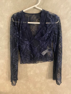 Mörkblå spetsblus från SHEIN - Snygg mörkblå blus i transparent spets från SHEIN. Blusen har djup v-ringning, långa ärmar och är tillverkad i ett stretchigt spetsmaterial som ger en trendig look. 