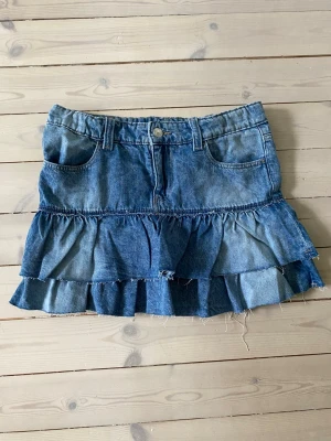Blå jeanskjol med volanger - Säljer en jeanskjol från Gina Tricot då den är för liten för mig. Den är i väldigt gott skick, utan defekter. Perfekt inför sommaren💕
