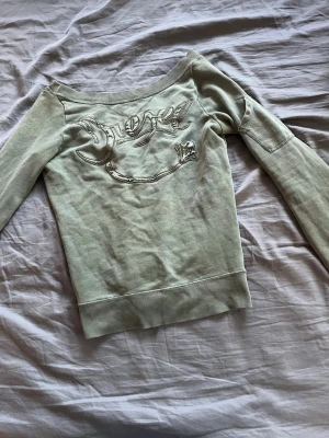 Offshoulder topp från Diesel - Snygg offshoulder topp från Diesel i ljusbeige färg med broderad logga framtill. Toppen har långa ärmar och bred ribbad kant nedtill. Perfekt för dig som vill ha en unik och trendig look.
