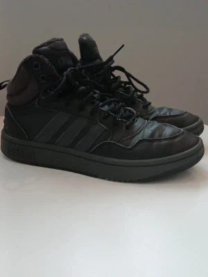 Svarta Adidas kängor med skön fodring - OBS pris kan enkelt diskuteras                              Köpte dom men tyvärr så passade dom inte. Säljer ett par svarta Adidas kängor med klassiska tre ränder på sidan och högt skaft. Skorna har snörning, vadderad plös och krage samt mjukt foder för extra komfort. 