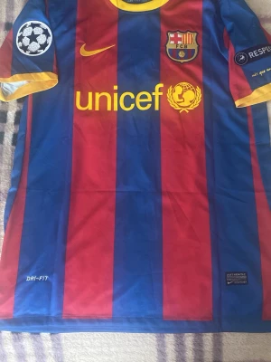 FC Barcelona Messi matchtröja - Säljer en officiell FC Barcelona matchtröja från Nike med Messi 10 på ryggen. Tröjan har blå och röda vertikala ränder, gula detaljer och Champions League-patchar på ärmarna. Materialet är lätt och andas med Dri-FIT-teknologi. Perfekt för fotbollsfans! Finns en liten defekt på sista bilden. Helt ny med tagg. Priset är ej hugget i sten!