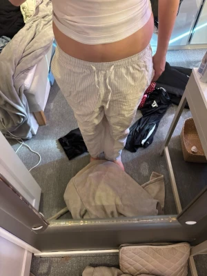 Randiga pyjamasbyxor i bomull - Säljer ett par bekväma loungewear-byxor i vitt med tunna bruna ränder. Byxorna har resår och dragsko i midjan för skön passform. Perfekta för att chilla hemma. Materialet känns mjukt och luftigt men dock har de två fläckar. 