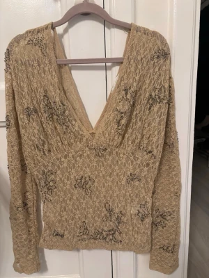 Beige spetsblus med v-ringning Zara - Superfin beige blus i spets med djup v-ringning både fram och bak. Långärmad modell med broderade detaljer och lätt transparent material. Perfekt för dig som gillar romantisk och unik stil.