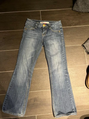 Blå bootcut jeans från Only - Snygga blå bootcut jeans från Only med klassisk femficksdesign och ljusa slitningar framtill. Jeansen har normal midja och är tillverkade i denim med lätt stretch för skön passform. Perfekta för en avslappnad och trendig look.