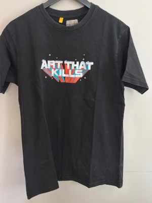 Svart t-shirt Gallery Dept. - Svart t-shirt från Gallery Dept. med tryck på både fram- och baksidan. Framsidan har texten 'ART THAT KILLS' i färgglada bokstäver och baksidan har 'GALLERY DEPT.' i gult och blått. Klassisk passform och rund hals.