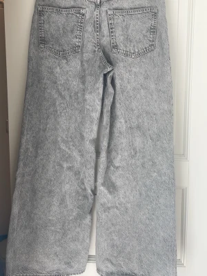 Grå wide leg jeans med acid wash - Säljer ett par gråa wide leg jeans med cool acid wash-effekt. Jeansen har klassiska fem fickor, hög midja och raka, vida ben. Materialet är denim och de har en modern, avslappnad passform som är perfekt för dig som gillar streetstyle. Devided från hm.